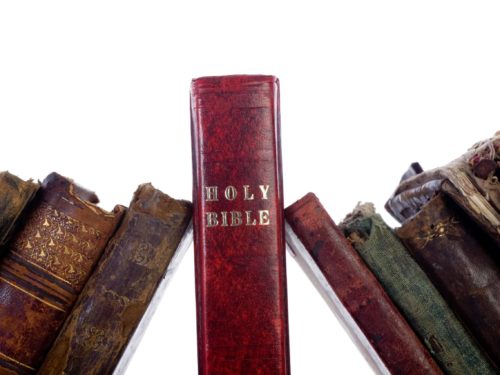 Antique books leaning on holy bible
