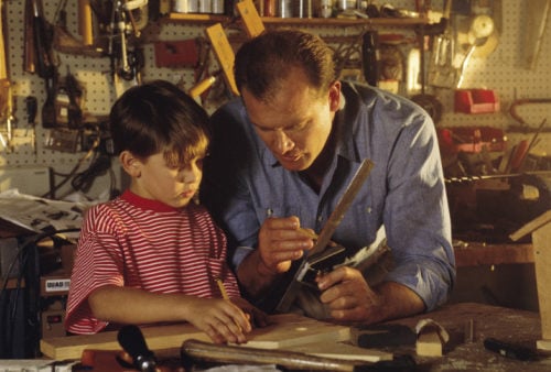 father showing son woodworking technique as a rite of passage into manhood