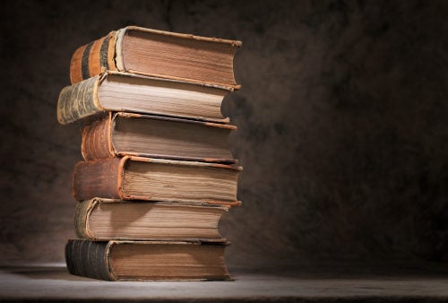 stack of very old, thick books on a table, similar to the books written by Ellen G. White