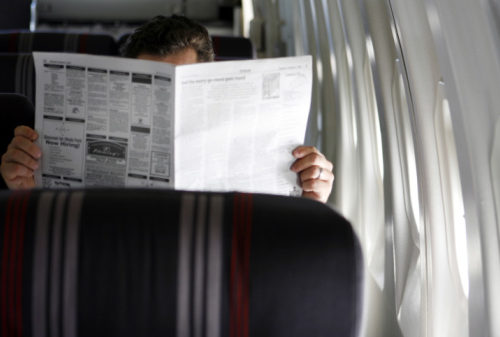 Man reading a newspaper in an airplane