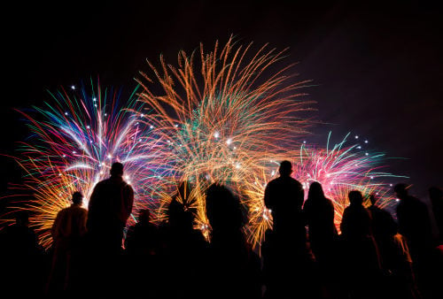 Big fireworks with silhouetted people in the foreground watching