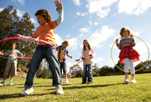 Five children (7-12) playing with plastic hoops in park