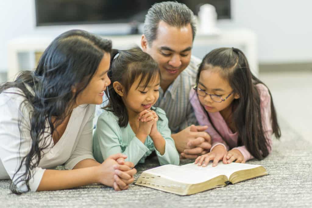 young family lying on floor learning about the importance of the bible in their daily life