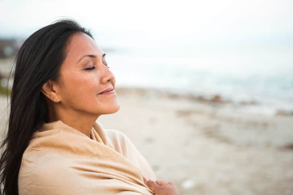 woman at seaside happy that the bible has helped her daily life