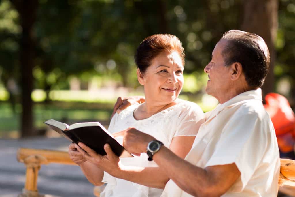 man and woman on park bench reading about how the bible can help with their daily life