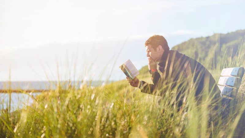 Man sitting outdoors looking at a book