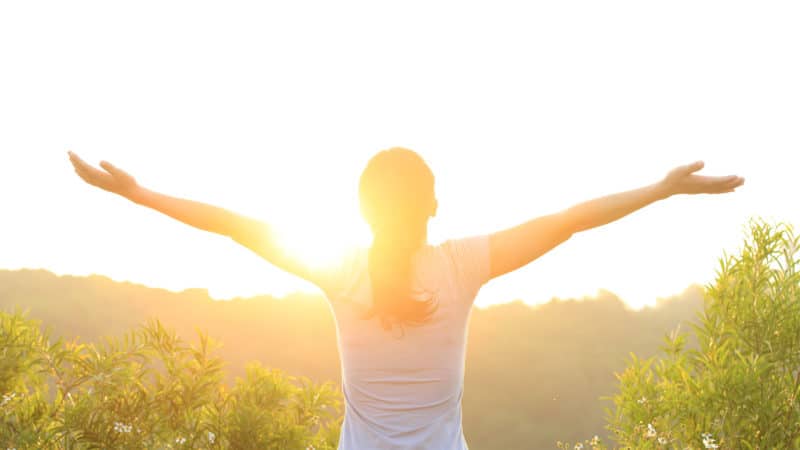 woman standing in the sunshine with outstretched arms Woman with outstretched arms during golden hour