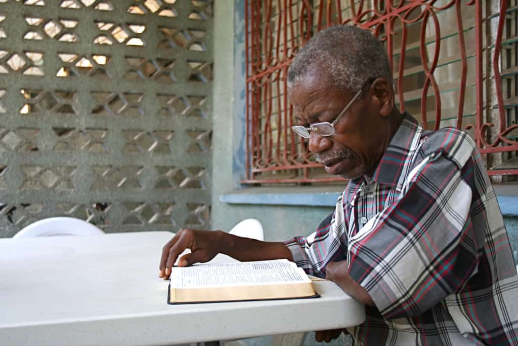 older man sitting at table beginning to study his bible