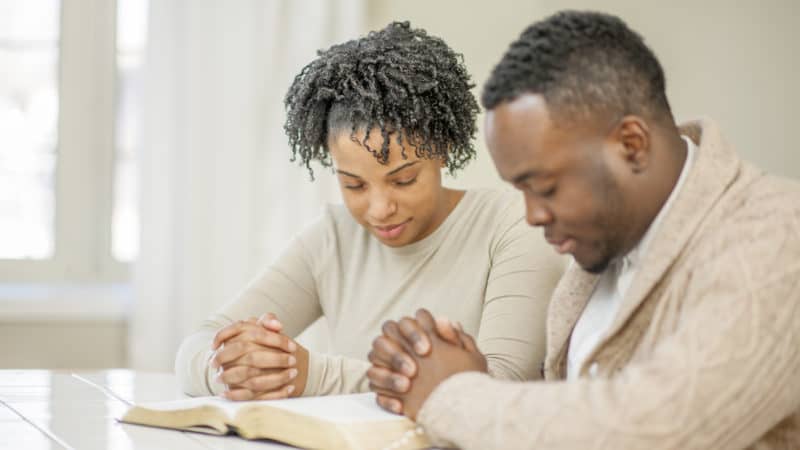 Couple prays with open Bible