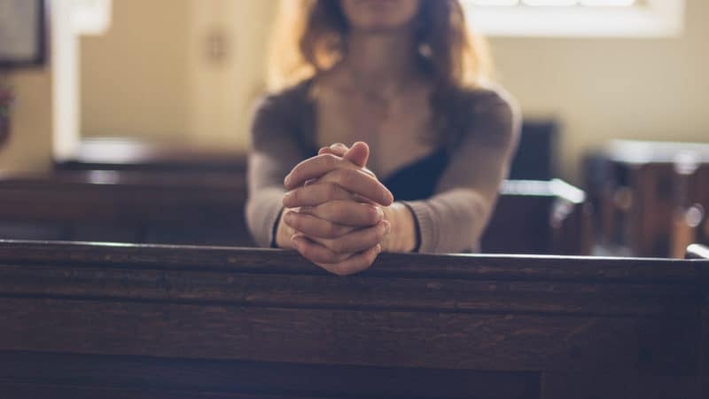 woman praying woman praying in church pew on Sabbath