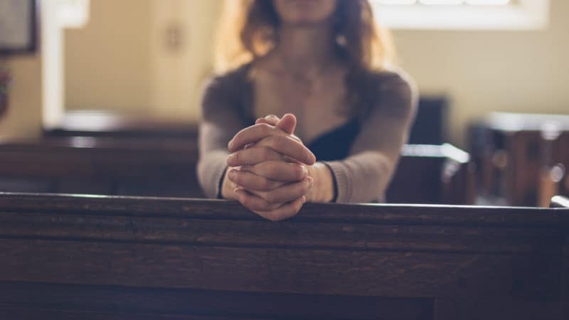 woman praying in church pew on Sabbath