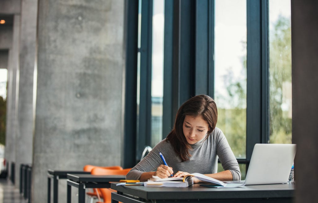 young woman in the library studying her bible