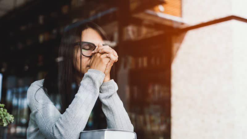 Woman praying at table with Bible