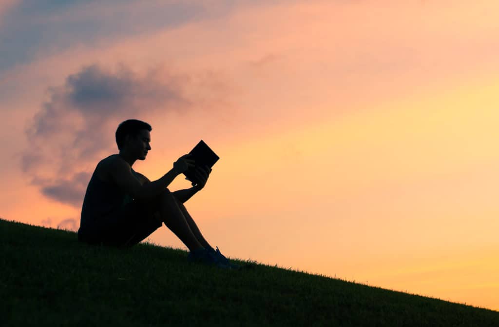 man sitting on a hill at sunset eager to learn how to study the bible