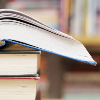 a stack of three books in a library which are being used as tools for getting a good education