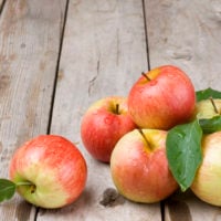 six red and yellow apples on a wooden table which are part of a healthy diet