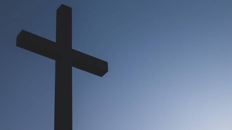 silhouette of cross against blue sky as a symbol of salvation in jesus