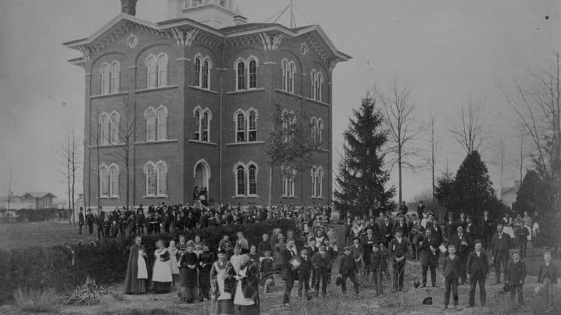 black and white large 3 story house with many adventist members standing in the front yard