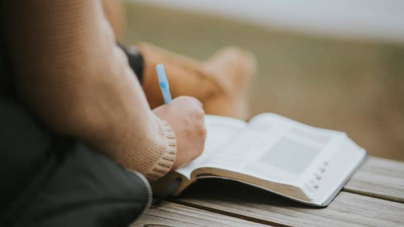 Person marking Bible outdoors