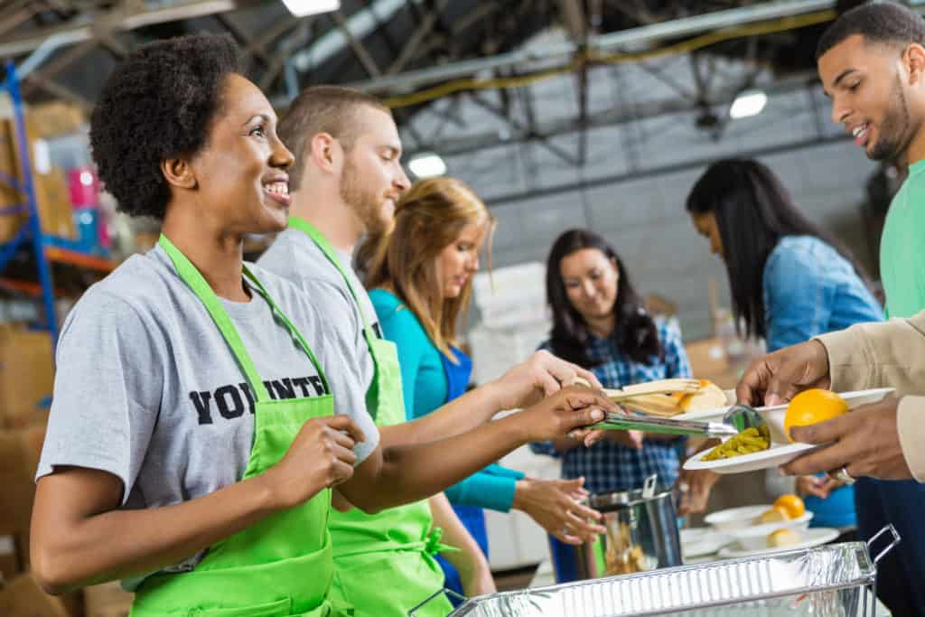 group of adventist volunteers standing at table handing out meals to community members