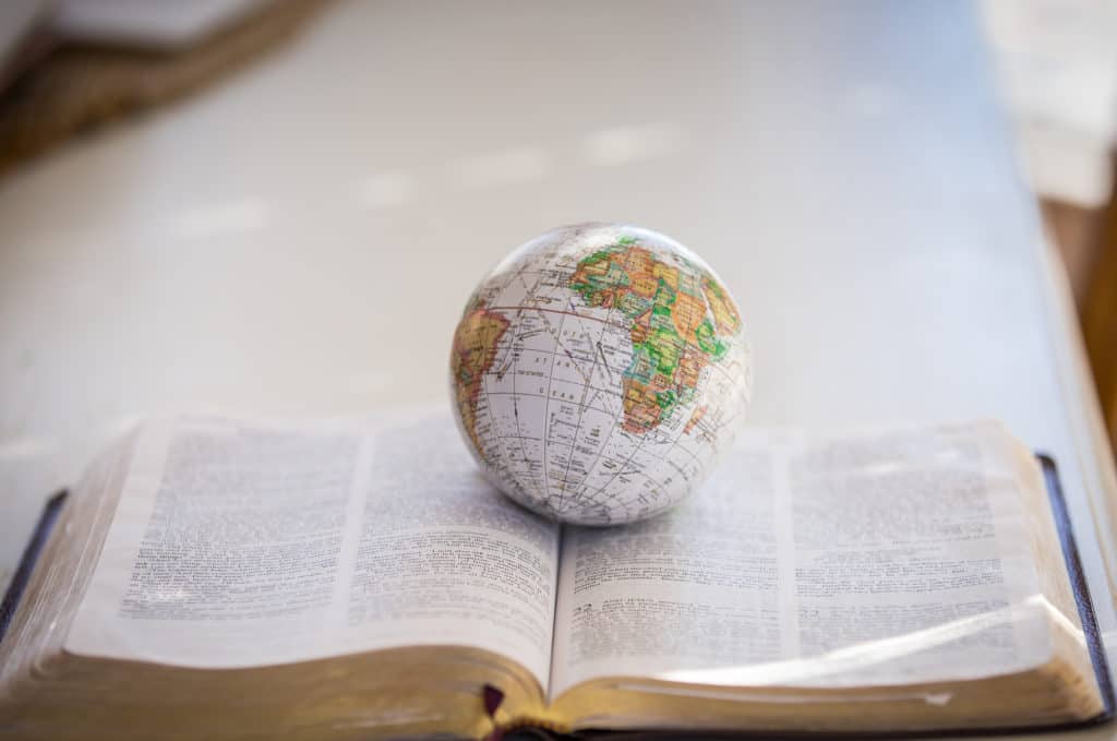 Small globe sitting on open Bible