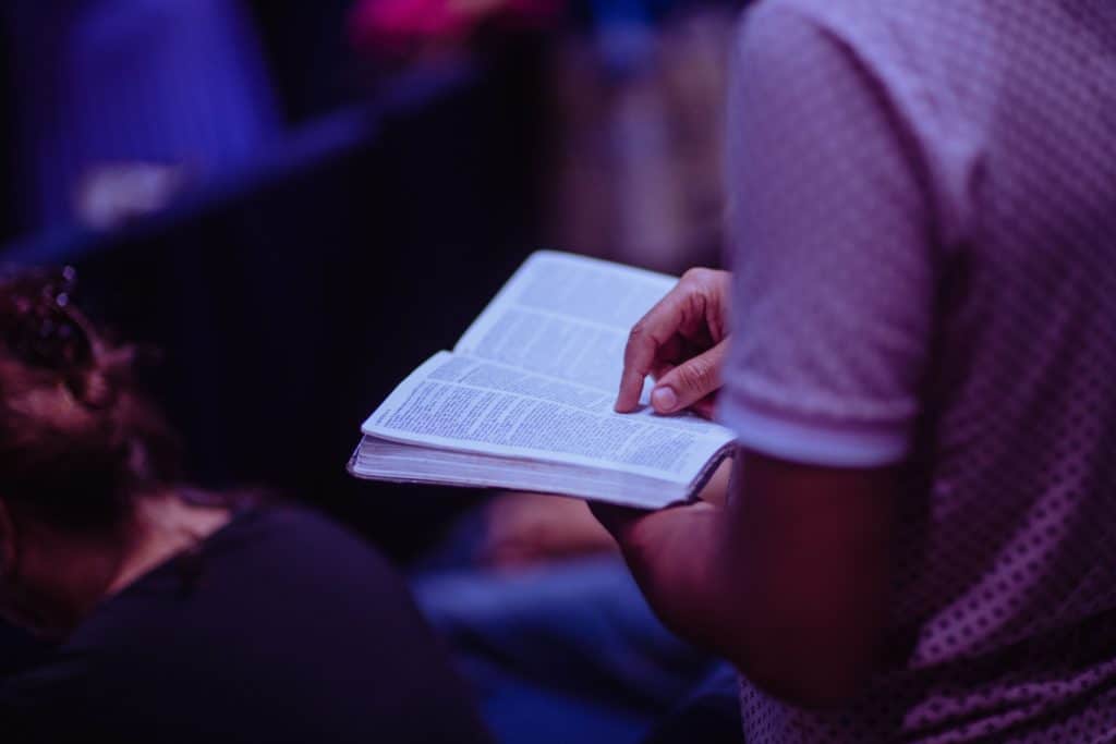 man standing in Adventist church with open Bible in his hand