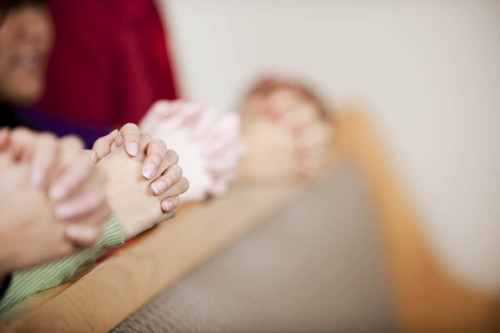 Hands praying in a church service together during the end times.