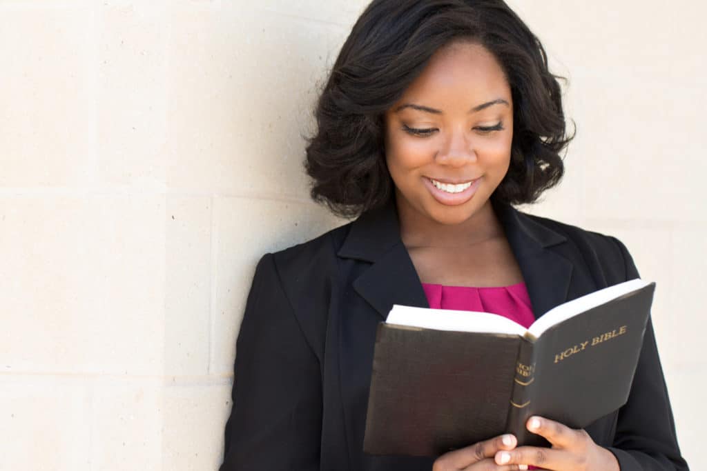 An African American woman dressed for Sabbath, reading her Bible.