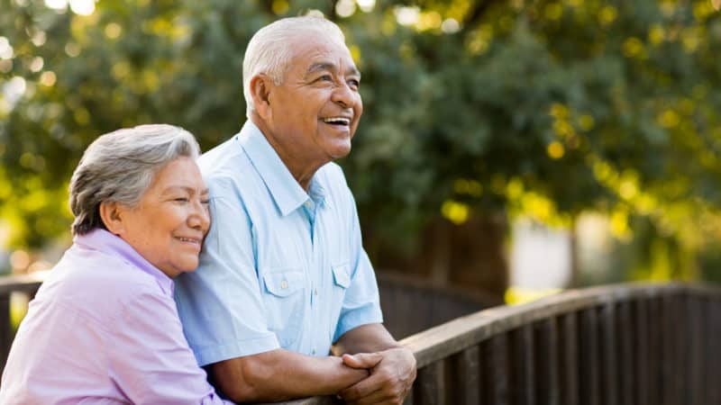 A senior couple enjoy their afternoon on a bridge.