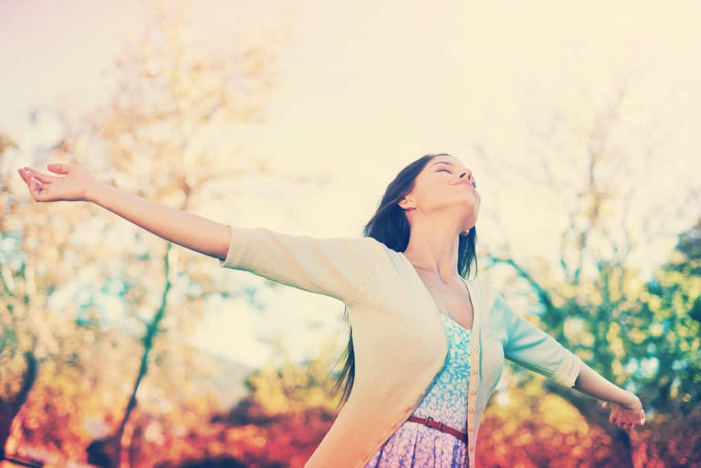 Woman with hands outstretched outside, enjoying God’s creation.