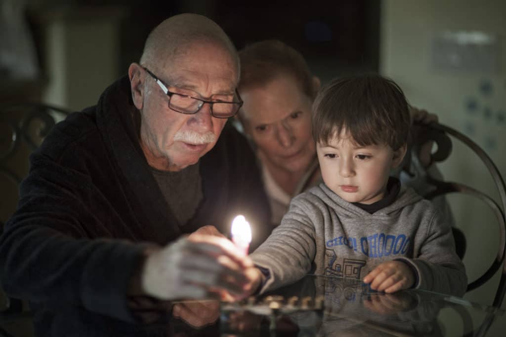 Family with grandparents and grandson lighting candles 