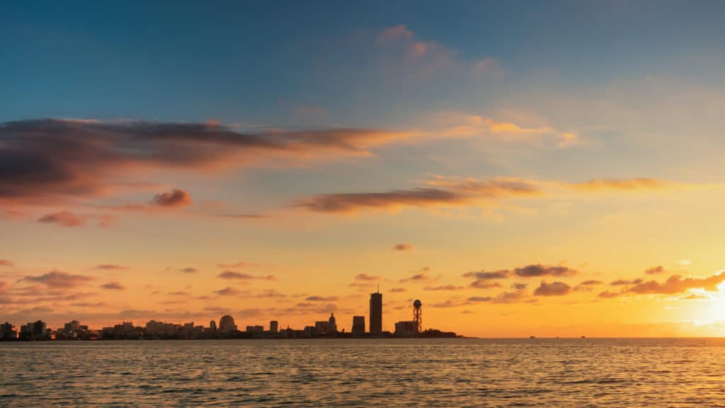 The sun setting for Sabbath on Friday behind a peaceful cityscape and lake.