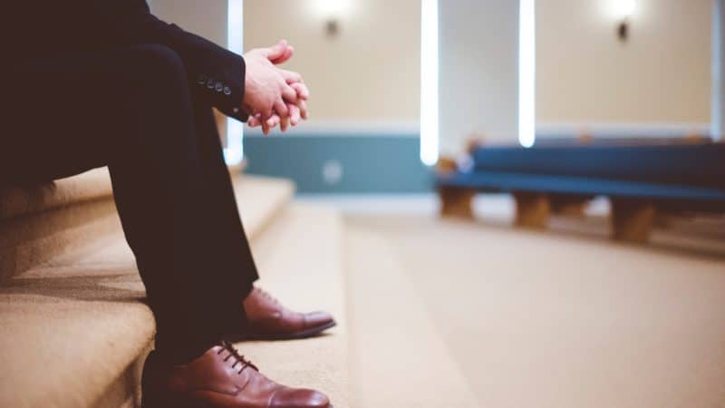 A pastor praying in the front of the church santuary before giving the congregation the Sabbath sermon.