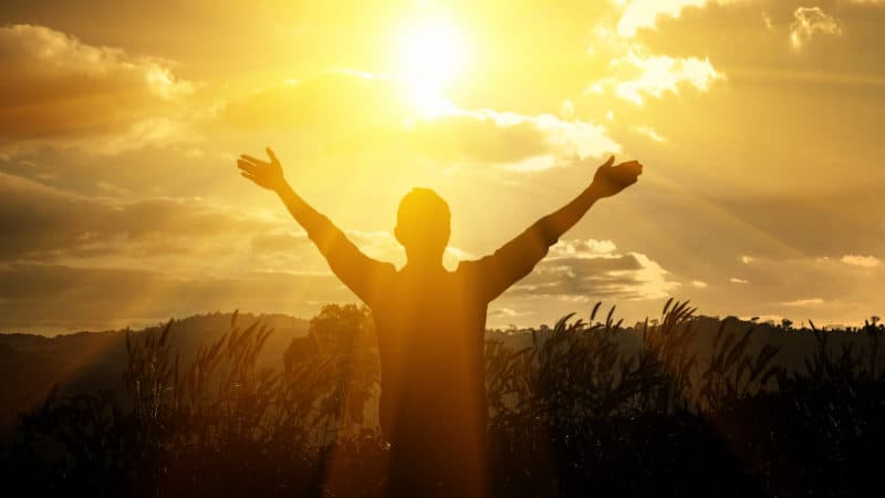 silhouette of man at sunset standing with arms outstretched and thankful for his connection with God on Sabbath