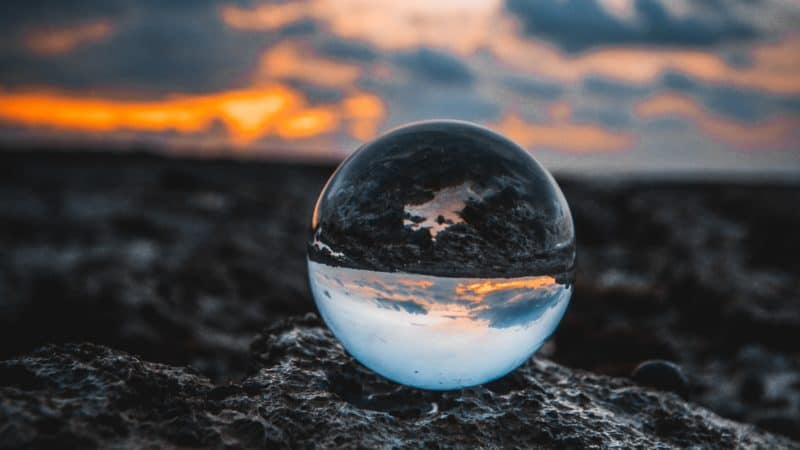 Glass orb sitting on a rock at sunset