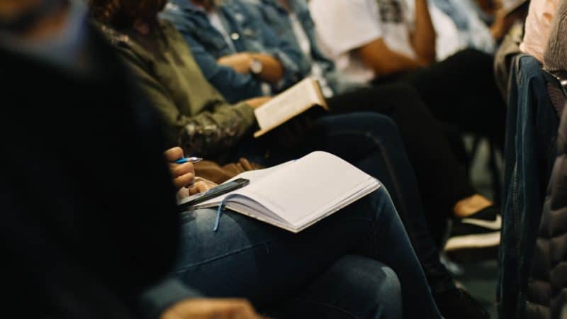 Person keeping notes with their Bible open at church
