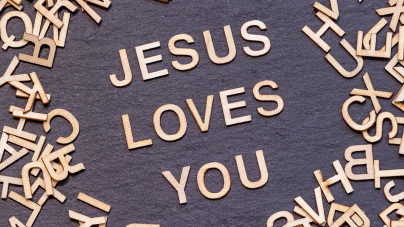 wooden letters JESUS LOVES YOU on dark slate background