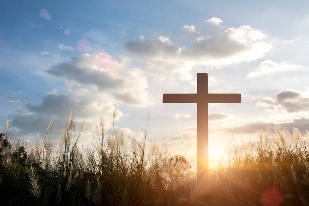 The cross with the sun setting behind it.