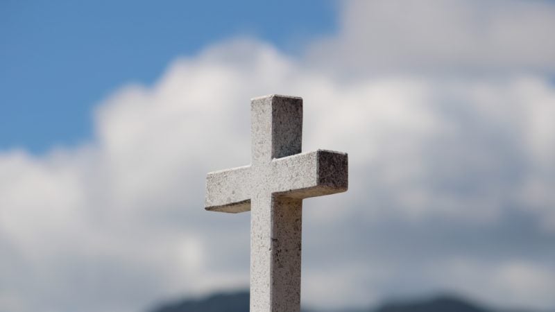 Stone Cross with clouds behind.