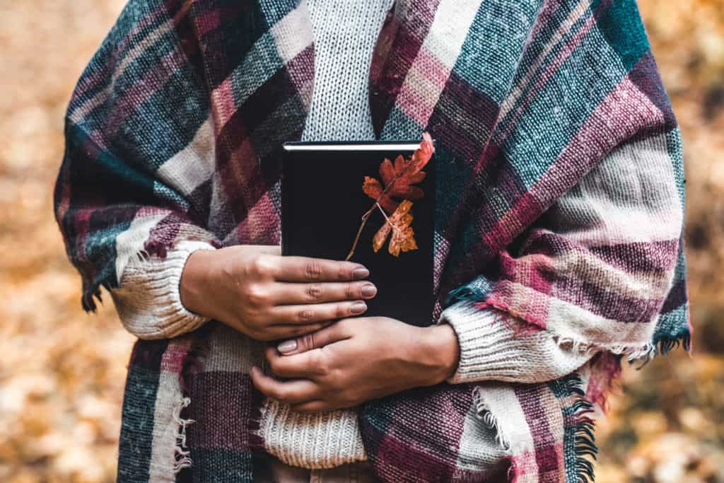 Close-up of a woman holding a Bible in her hands outside in autumn