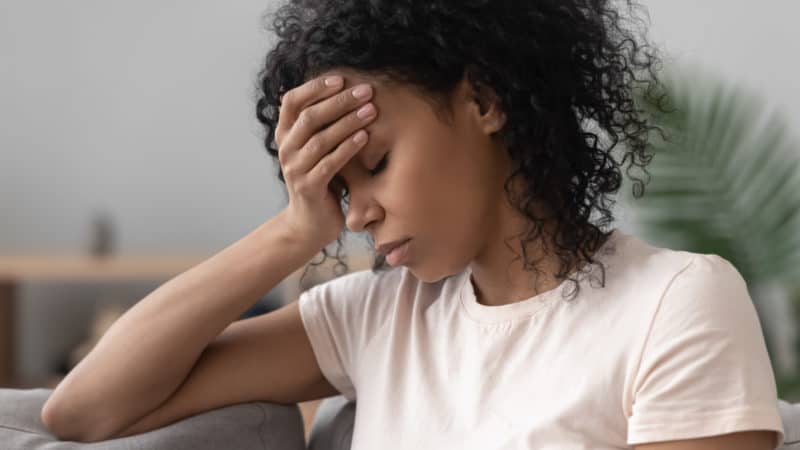 Close up of unhappy woman on couch as we learn to lay our burdens on Jesus and He strengthens us