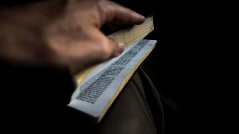 A hand opening a Bible.