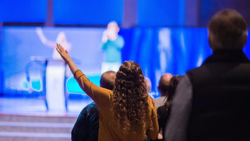 A woman at church with her hand raised in praise