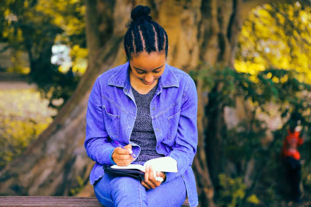 A young girl sitting outside and studying her Bible