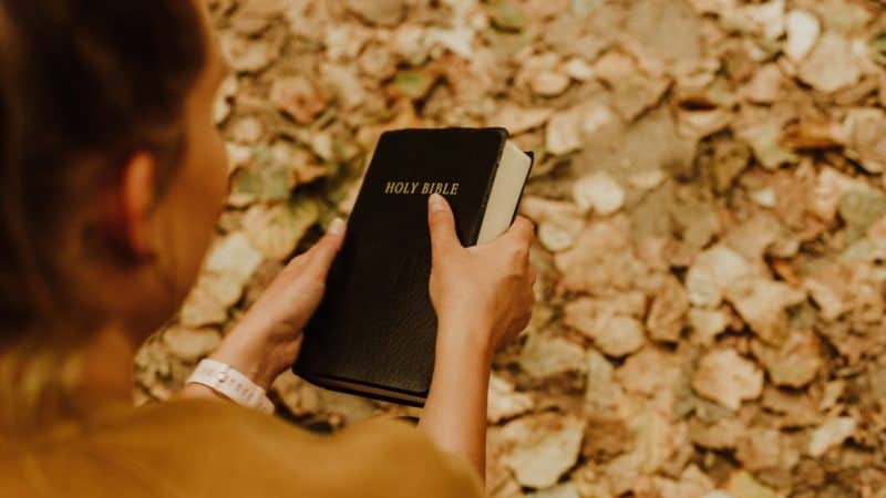 A woman holding a Bible outside as we learn of gift of power of choice from God and choose to follow Him