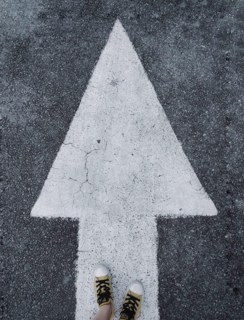 An arrow on the road with feet pointing forward. 