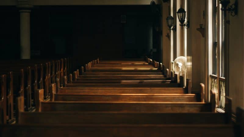 Church interiors with the sun shining through the windows onto the pews.