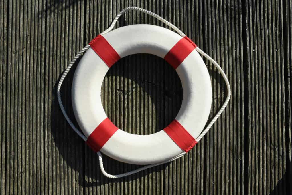 overhead view of a round red and white life preserver on wooden surface