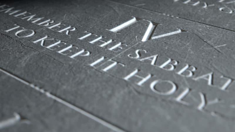 closeup of the ten commandments etched in a stone tablet highlighting the fourth