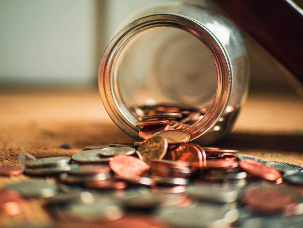 A jar tipped over with coins spilling out.